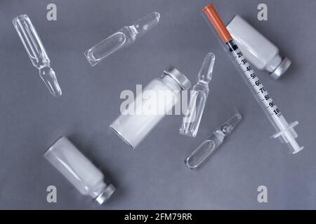 Medikamente in Vials und Ampullen, unverdünnt und flüssig für Injektionen, Spritzen für Injektionen auf grauem Hintergrund. Stockfoto