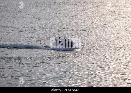 Guatapé, Antioquia, Kolumbien - April 3 2021: Lateinischer Mann fährt einen Jetsky im Wasser des Staudamms bei Sonnenuntergang Stockfoto