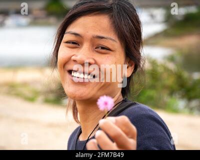 Guatape, Antioquia, Kolumbien - April 4 2021: Junge Asiatin mit einer kleinen Blume und Blick auf die Kamera Stockfoto