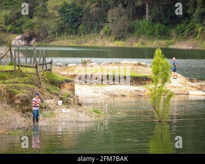 Guatape, Antioquia, Kolumbien - April 4 2021: Alter Mann in blauer Jeans und schwarzen Stiefeln Fliegenfischen am Flussufer Stockfoto