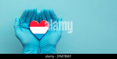 Ärzte Hände tragen chirurgische Handschuhe mit Herznote der Luxemburger Flagge Stockfoto