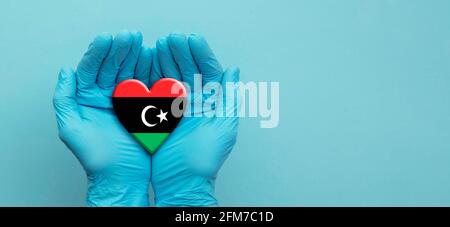 Ärzte Hände tragen chirurgische Handschuhe halten Libyen Flagge Herz Stockfoto
