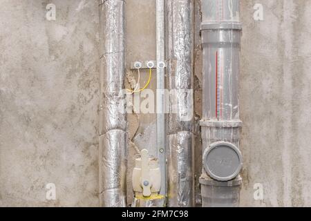 Wärmedämmsystem, runde Brandleitungen und isolierende elektrische Leitungen in einem Gebäude auf einer Baustelle. Stockfoto