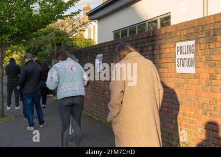 Sonnenuntergangsstrahlen werfen auf Wähler vor dem Wahllokal für die britischen Wahlen 2021, 6. Mai. „Super Thursday“, ein Wahlmonster, Greater London Greenwich, Stockfoto