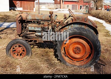 Umea, Norrland Schweden - 20. März 2021: Alter rostiger Traktor, der auf dem Hof verlassen steht Stockfoto