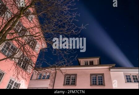 Ein Lichtstrahl vom Dachfenster in den Nachthimmel über den Häusern in Zürich Stockfoto