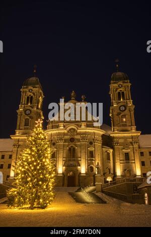 Die Benediktinerabtei Einsiedeln mit ihrer mächtigen Basilika ist das wichtigste katholische Wallfahrtszentrum der Schweiz. Weihnachtsbaum und verschneite Winter ni Stockfoto