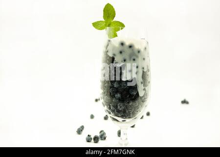 Glastasse mit blauen Beeren und Joghurt geschmückt mit Blättern und Minze, frische und nahrhafte vegetarische Gerichte in Mexiko-Stadt frei von Zucker Stockfoto