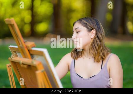 Petite junge asiatische Frau Student Malerei im Park mit Ein Kabinett-Easel Stockfoto