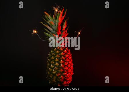 Getönte frische Ananas mit Glitzern auf dunklem Hintergrund Stockfoto