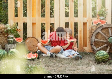 Kinder, die im Sommer ein Picknick machen. Kinder spielen und essen Wassermelone. Stockfoto