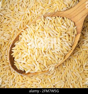 Draufsicht auf ungekochte Risoni pastina in Holzlöffel aus der Nähe Stockfoto