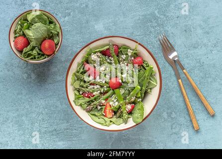 Köstlicher gesunder Salat aus frischen Erdbeeren, grünem Spargel, Feta-Käse, Rucola, Salat. Sauberes Essen, Lunchschüssel. Draufsicht. Stockfoto