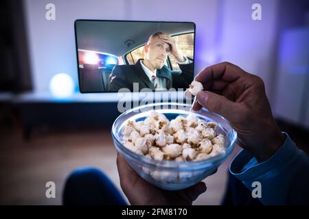 Genießen Sie Popcorn-Snacks beim Fernsehen oder Fernsehen auf dem Sofa Stockfoto