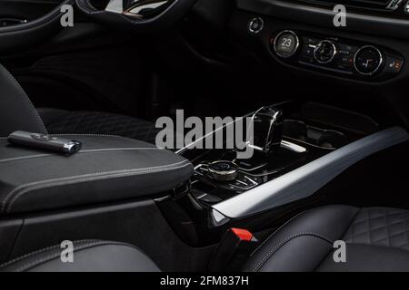 Schwarzer Innenraum eines modernen Autos. Schwerpunkt auf Schalthebel und Armaturenbrett. Innenausstattung aus schwarzem Leder. Stockfoto