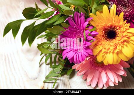 Nahaufnahme eines schönen bunten Straußes von Gerbera Blumen auf Holztisch Hintergrund. Grußkarte mit Platz für die Beschriftung. Einrichtung im botanischen Stil Stockfoto