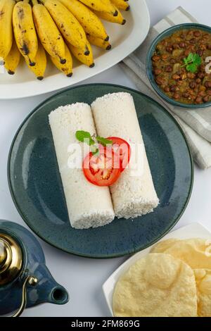 PUTTU -Kerala besonderes Frühstück mit Reismehl, das in einem aquarustic Teller mit Stücken von Paapad, Schüssel mit dem Kerri und Banane platziert angeordnet ist Stockfoto
