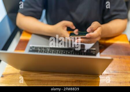 Frau Hand mit Smartphone und arbeiten auf Laptop Stockfoto