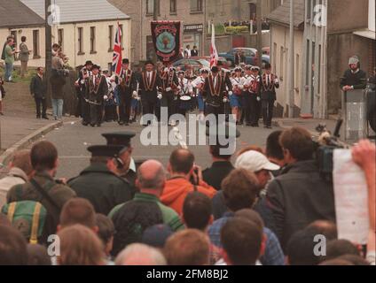 MITGLIEDER DER ROYAL BLACK PRECEPTORY MARSCHIEREN IN DIE ORANGE HALLE IN BELLAGHY COUNTY LONDONDERRY REIHEN DER POLIZEI IN VOLLEM UMFANG RIOT GEAR STAND ZUR SEITE Stockfoto