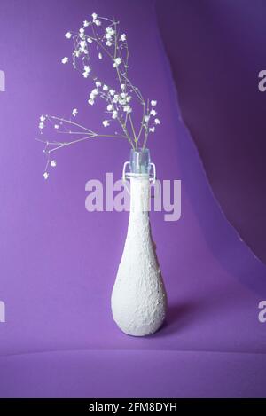 Blume in Vintage-Flasche auf drei Schichten trendigen Lavendel violetten Hintergrund. Minimalistisches, abstraktes Dekor und Raumkonzept. Mit Kopierbereich. Stockfoto