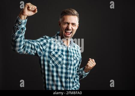 Bild eines hübschen glücklichen, aufgeregten grauhaarigen Mannes, der den Sieger zeigt Geste isoliert über grauem Wandhintergrund Stockfoto