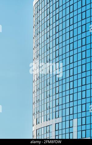 Stilvolles Bürogebäude in einem Hochhaus mit einer glänzenden blauen Glasfassade Helles Sonnenlicht gegen klaren blauen Himmel an sonnigen Tagen Stockfoto