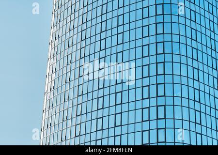 Stilvolles Bürogebäude in einem Hochhaus mit einer glänzenden blauen Glasfassade Helles Sonnenlicht gegen klaren blauen Himmel an sonnigen Tagen Stockfoto