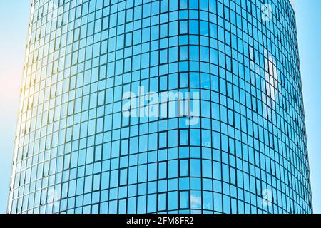 Stilvolles Bürogebäude in einem Hochhaus mit einer glänzenden blauen Glasfassade Helles Sonnenlicht gegen klaren blauen Himmel an sonnigen Tagen Stockfoto