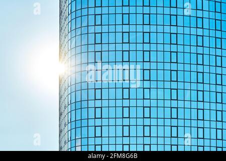 Stilvolles Bürogebäude in einem Hochhaus mit einer glänzenden blauen Glasfassade Helles Sonnenlicht gegen klaren blauen Himmel an sonnigen Tagen Stockfoto