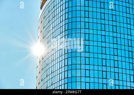 Stilvolles Bürogebäude in einem Hochhaus mit einer glänzenden blauen Glasfassade Helles Sonnenlicht gegen klaren blauen Himmel an sonnigen Tagen Stockfoto