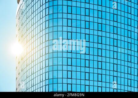 Stilvolles Bürogebäude in einem Hochhaus mit einer glänzenden blauen Glasfassade Helles Sonnenlicht gegen klaren blauen Himmel an sonnigen Tagen Stockfoto