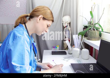 Eine Ärztin mittleren Alters arbeitet an einem Laptop. Arztpraxis, medizinische Geräte. Stockfoto