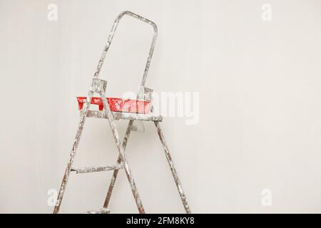 Konzept Malerei Arbeit Reparatur Malerei. Metall Leiter, Farbdosen in einem weißen Raum für die Reparatur Stockfoto