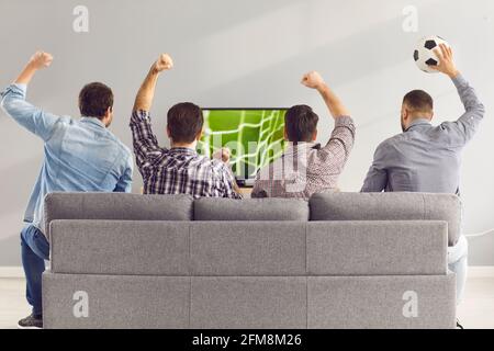 Männer versammelten sich zu Hause, um ein Fußballspiel auf der Couch vor dem Großbildfernseher zu sehen. Stockfoto