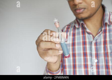 Junger Mann hält einen Insulinstift in der Hand Stockfoto