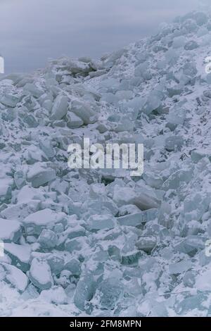 Vertikale Aufnahme von Eisstücken bedeckt mit Schnee auf dem Seacoast - für Hintergrund und Texturen Stockfoto