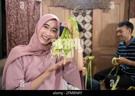 Aufgeregt asiatische muslimische Frau Herstellung Ketupat Reis Stockfoto