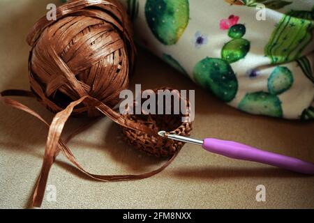 Handarbeit, Häkeln, Ball aus Naturgarn Bast und Häkelnadeln auf einem Sofa. Umweltfreundlicher Style. Hobby Zeit zu Hause. Stockfoto