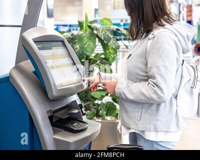 KAIRO, ÄGYPTEN - 06. Mai 2021: SCHALTER DER Fluggesellschaft EGYPTAIR für den Self-Check-in am Flughafen Kairo. Frau, die am Flughafen einen Selbstbedienungsautomaten für den Check-in benutzt, PR Stockfoto