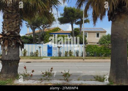 Weiß-blaues Haus zwischen Palmen in Palavas les Flots, in der Nähe von Carnon Plage und Montpellier, in der Region von okzitanien, Südfrankreich Stockfoto