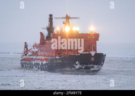 Sabetta, Region Tjumen, Russland - 4. April 2021: Der 50 ließ Pobedy Eisbrecher zieht in Eis. Bewölkt, leichter Schnee fällt. Stockfoto