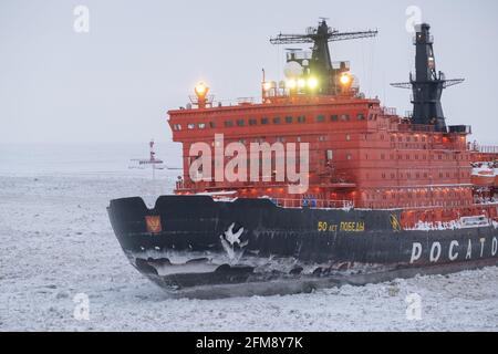 Sabetta, Region Tjumen, Russland - 4. April 2021: Der 50 ließ Pobedy Eisbrecher zieht in Eis. Bewölkt, leichter Schnee fällt. Stockfoto