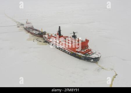 Sabetta, Region Tjumen, Russland - 4. April 2021: Der 50 ließ Pobedy Eisbrecher einen Tanker auf dem Eis schleppen. Bewölkt, leichter Schnee fällt. Stockfoto