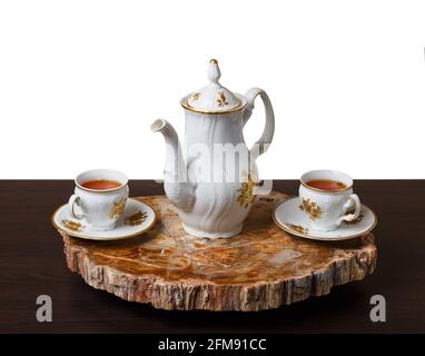 Elegantes Kaffeeset auf einem exklusiven Tablett aus einem Schnitt aus altem versteinertem Holz. Isoliert auf weißem Hintergrund. Stockfoto