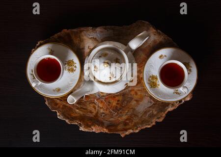 Elegantes Kaffeeset auf einem exklusiven Tablett aus einem Schnitt aus altem versteinertem Holz. Draufsicht. Stockfoto