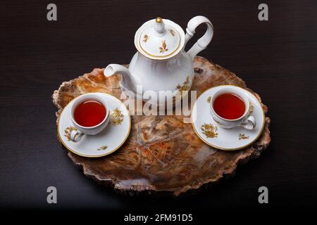 Elegantes Kaffeeset auf einem exklusiven Tablett aus einem Schnitt aus altem versteinertem Holz. Draufsicht. Stockfoto