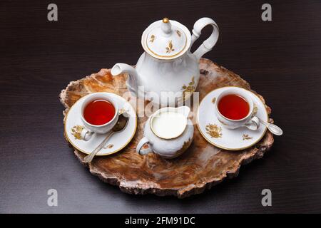 Elegantes Kaffeeset auf einem exklusiven Tablett aus einem Schnitt aus altem versteinertem Holz Stockfoto