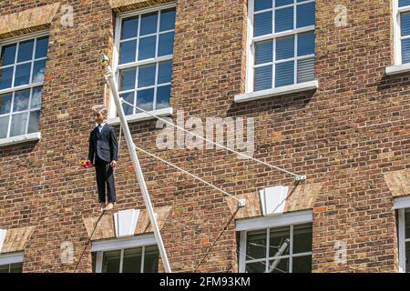 SAVILE ROW LONDON 7. MAI 2021. Eine Skulptur des italienischen Künstlers Maurizio Cattelan eines Mannes, der einen Blumenstrauß in der Savile Row London an einer Schlinge an einem Fahnenmast hält. Credit amer Ghazzal/Alamy Live News Stockfoto