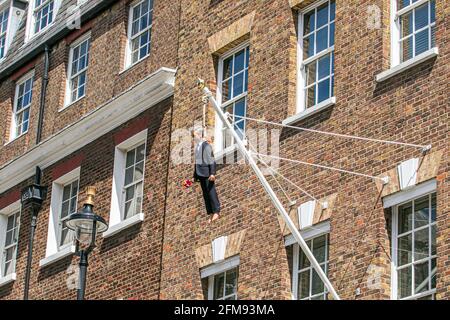 SAVILE ROW LONDON 7. MAI 2021. Eine Skulptur des italienischen Künstlers Maurizio Cattelan eines Mannes, der einen Blumenstrauß in der Savile Row London an einer Schlinge an einem Fahnenmast hält. Credit amer Ghazzal/Alamy Live News Stockfoto