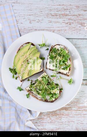 Roggenbrot mit Cerealien, Frischkäse, Avocado und Sprossen aus Rettich (mikrogrün) Stockfoto